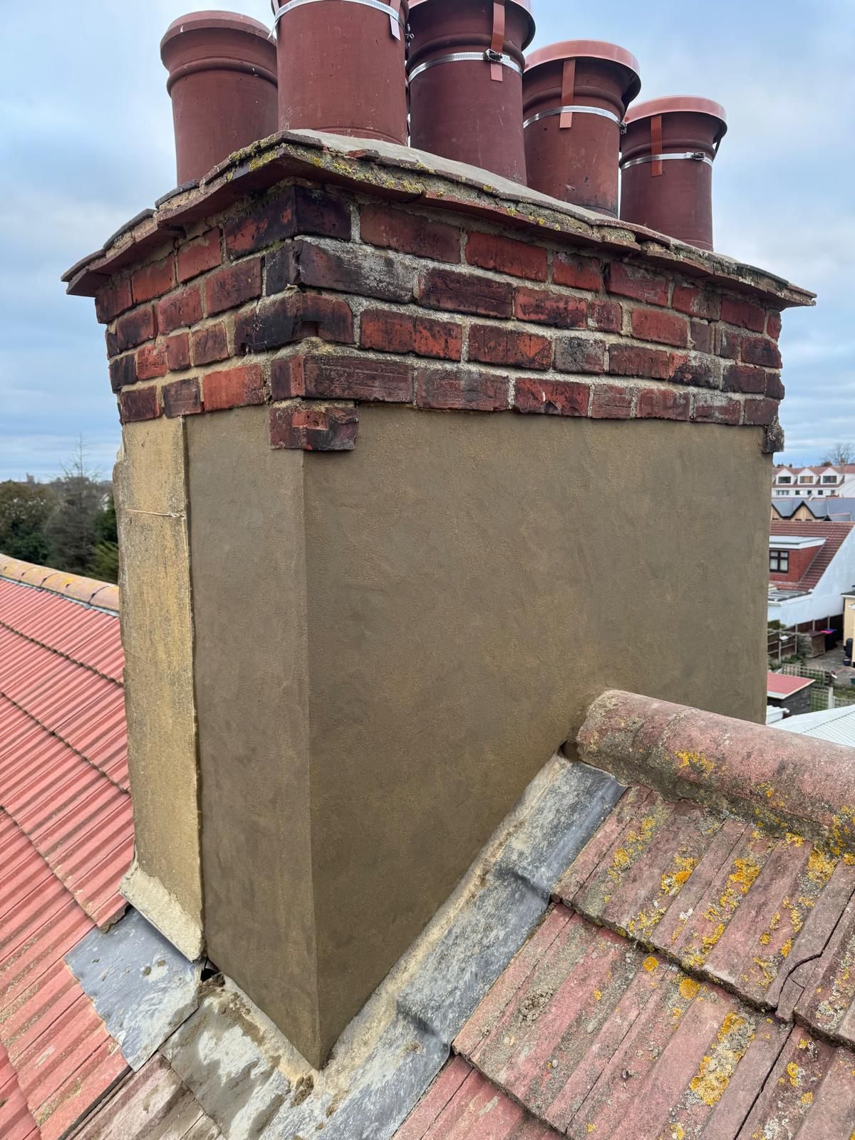 Newly tiled roof around a brick chimney stack